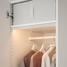 there is a closet with clothes hanging on the rack and two lights above it,