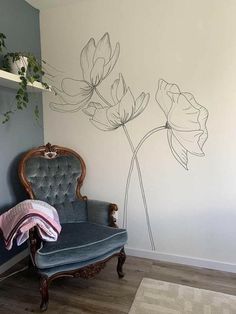 a chair sitting in front of a wall with flowers painted on it