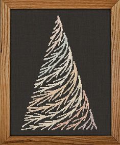 a cross - stitch christmas tree in a wooden frame on a black background with white and pink lines