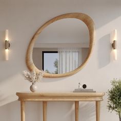 a wooden table sitting under a mirror next to a vase on top of a table