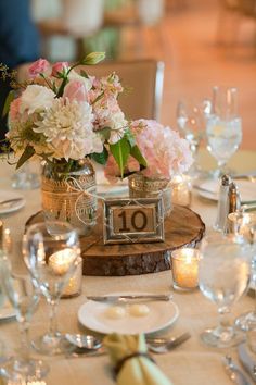 the table is set with silverware and pink flowers in vases on each side