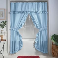 a bathroom with blue curtains and a red rug in front of the shower curtain that is open