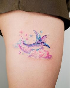 a woman's thigh with a dolphin tattoo on her left side and stars in the background