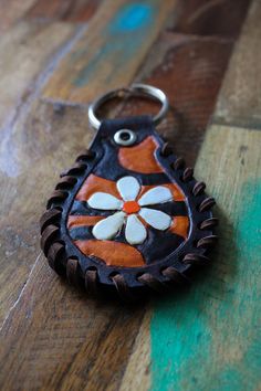 a keychain with a flower on it sitting on top of a wooden floor