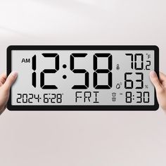 two hands holding up a digital clock with the time at 2 53 pm on it