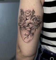 a woman's arm with flowers in the shape of a heart tattoo on it