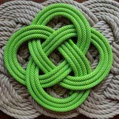 green rope is on top of two gray ropes, one knoted up and the other knoted down