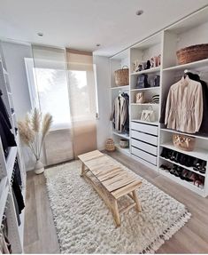 an organized closet with white shelving and wooden bench