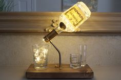 a light that is on top of a wooden table next to two glasses and a bottle