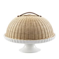 a white cake plate with a wicker dome on the top and bottom, holding a brown leather handle