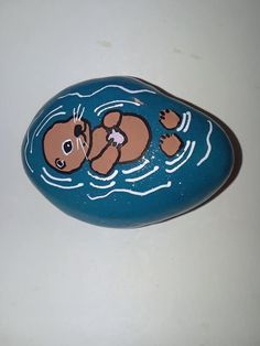 a painted rock with an image of a beaver floating on it's back in the water