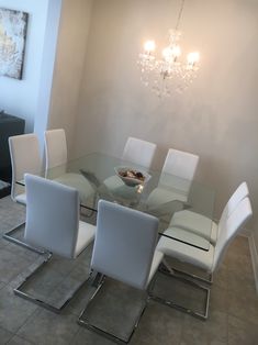 a glass dining table with white chairs around it