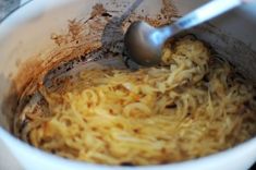 a white bowl filled with noodles and a ladle on top of the mixing bowl