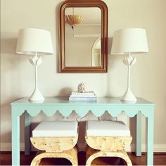 a blue table with two white stools and a mirror on the wall above it