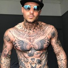 a man with tattoos on his chest wearing sunglasses and a cap is standing in front of a mirror