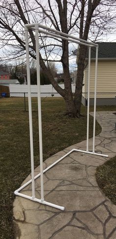 a white metal structure sitting on top of a sidewalk next to a tree and grass covered yard