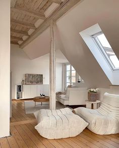 an attic with wooden floors and white furniture on the floor, in front of a skylight