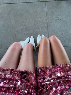 two women's legs with sequins and high heels on the ground, both wearing white shoes