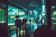 people walking down the street at night with an umbrella