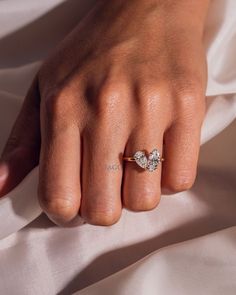 a woman's hand with a diamond ring on top of her finger and white satin