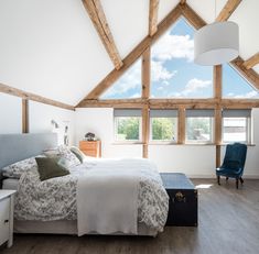 a bedroom with wooden beams and white walls, hardwood flooring and a large bed