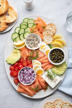 a white plate topped with lots of different types of food next to crackers and veggies