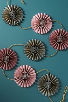 three paper fans are hanging on a wall next to a gold string and two other decorative items