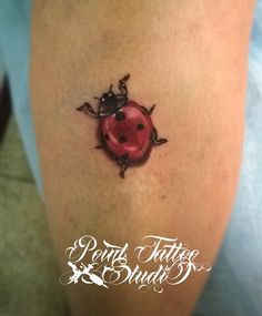 a ladybug tattoo on the leg of a woman