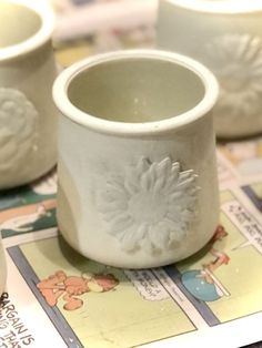 several white cups sitting on top of a table next to each other with designs on them