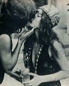 an old photo of two women kissing each other while sitting at a table with drinks in front of them