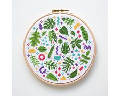 a cross - stitch pattern is displayed on a white surface with a wooden hoop frame