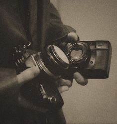 a person holding a camera in their hand with the lens up to their eyepiece