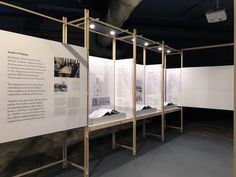 an exhibit with white walls and wooden frames on the wall is displaying information about architecture