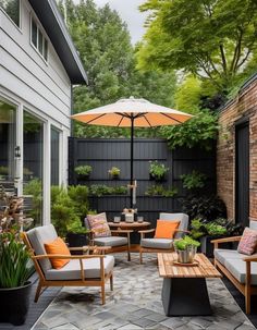 an outdoor living area with patio furniture, umbrella and potted plants on the ground