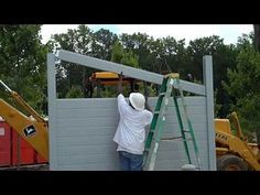 a man on a ladder working on a construction wall next to a bulldozer