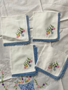 four embroidered napkins with flowers on them