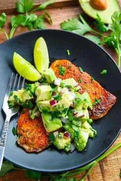 a black plate topped with meat and avocado