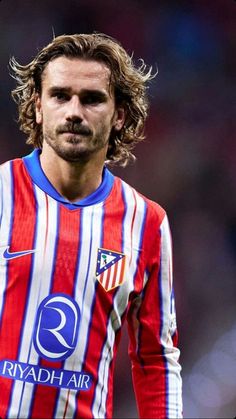 a man with long hair wearing a red and white striped shirt is looking at the camera