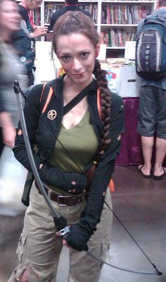 a woman is standing in front of a bookshelf and holding a large hose