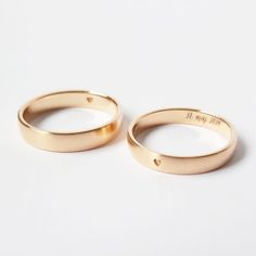 two gold wedding rings with the word love written on each one in cursive font