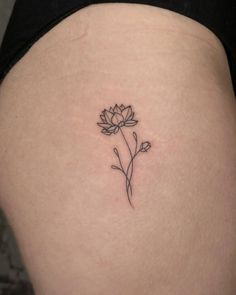 a small flower tattoo on the back of a woman's thigh