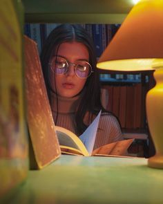 a girl reading a book in front of a lamp