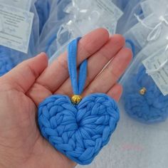 a hand holding a blue heart ornament in it's palm