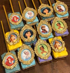 there are many disney princess cupcakes on the table with yellow sticks in front of them