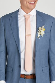 a man wearing a blue suit with a pink tie and flower boutonniere