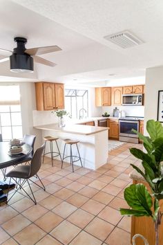 an open kitchen and dining room area with tile flooring, wood cabinets, counter tops, and ceiling fan