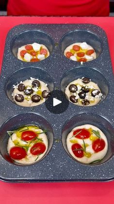 a muffin tin filled with mini pizzas on top of a red table