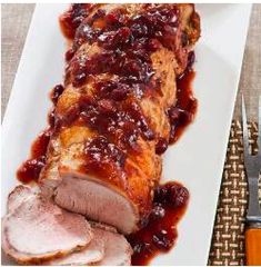 a white plate topped with meat covered in bbq sauce next to a fork and knife