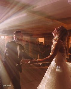 a bride and groom are dancing together at their wedding reception in the sunbeams