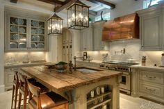 a kitchen with an island made out of wood and lights hanging from it's ceiling